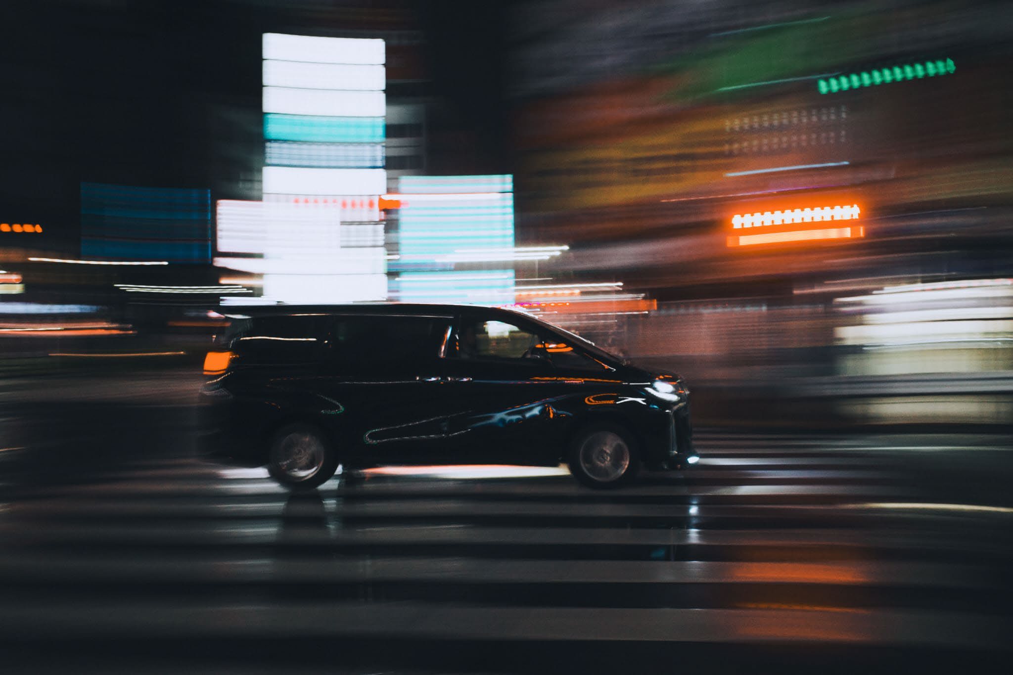 A car passing through a night-lit city street
