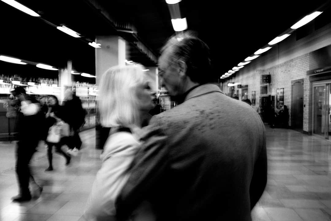 Blurred commuters passing a couple inside a station