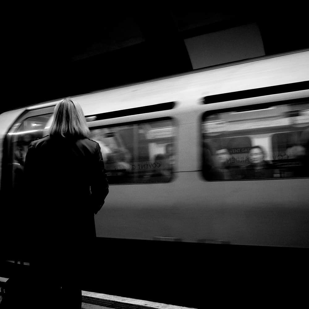A woman facing a train moving through a station
