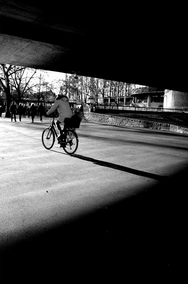 A cyclist crossing a sunlit street