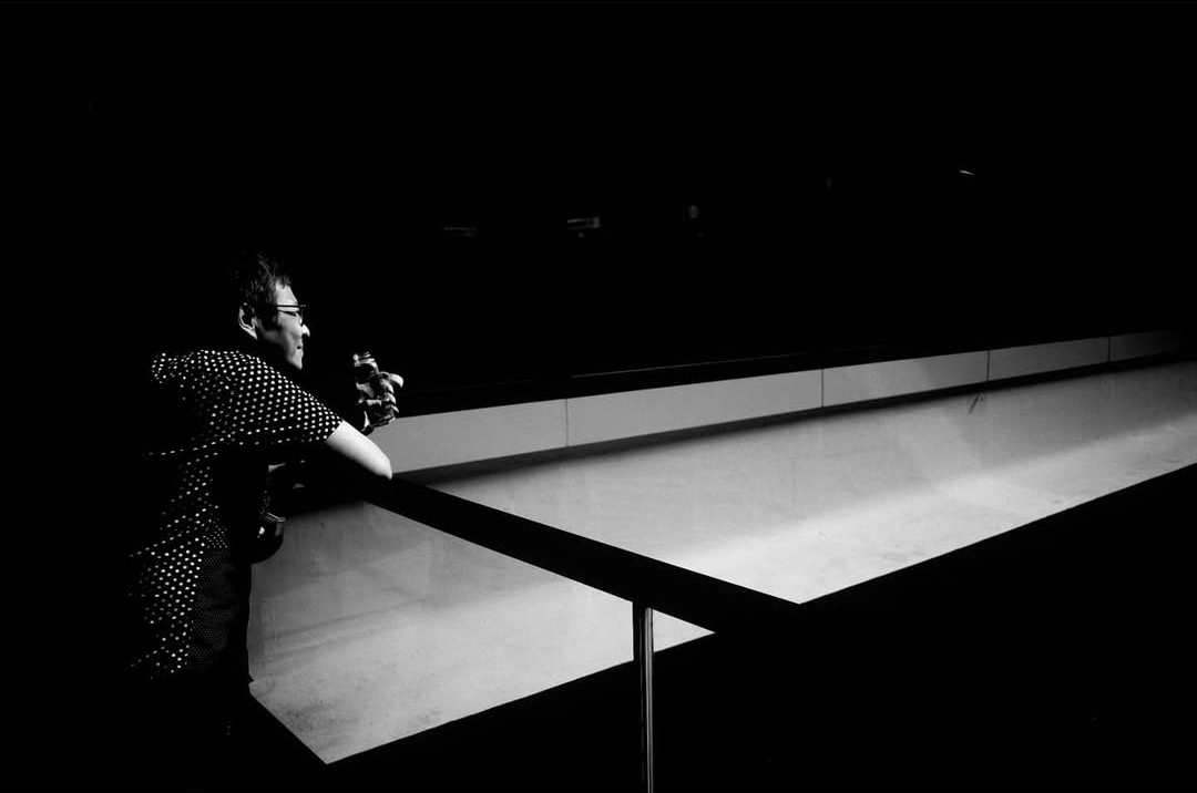 A seated figure isolated beside a pool of light
